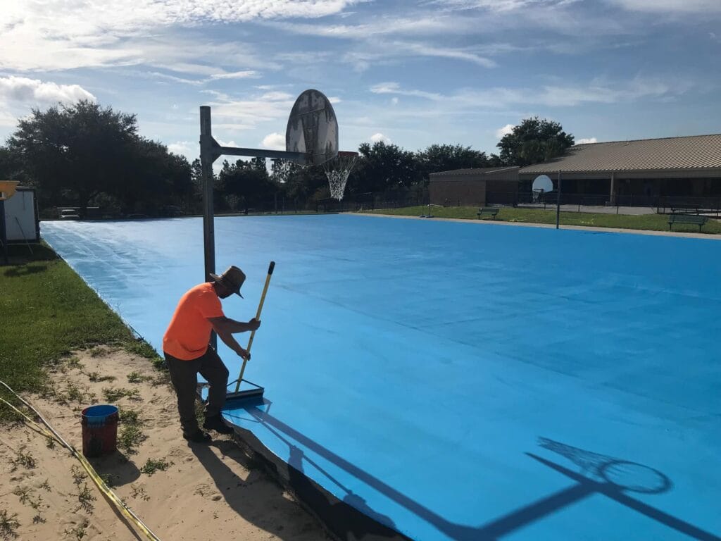 image of of man in process of resurfacing basketball court