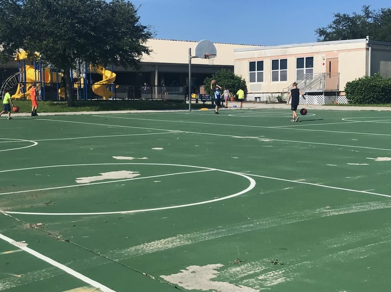 image of old and warn basketball court with kids playing ball
