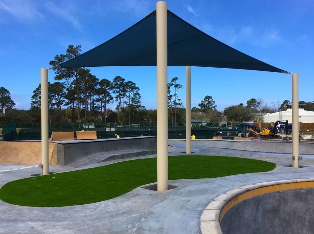 blue triangular shade erected between tall posts, covering turf area