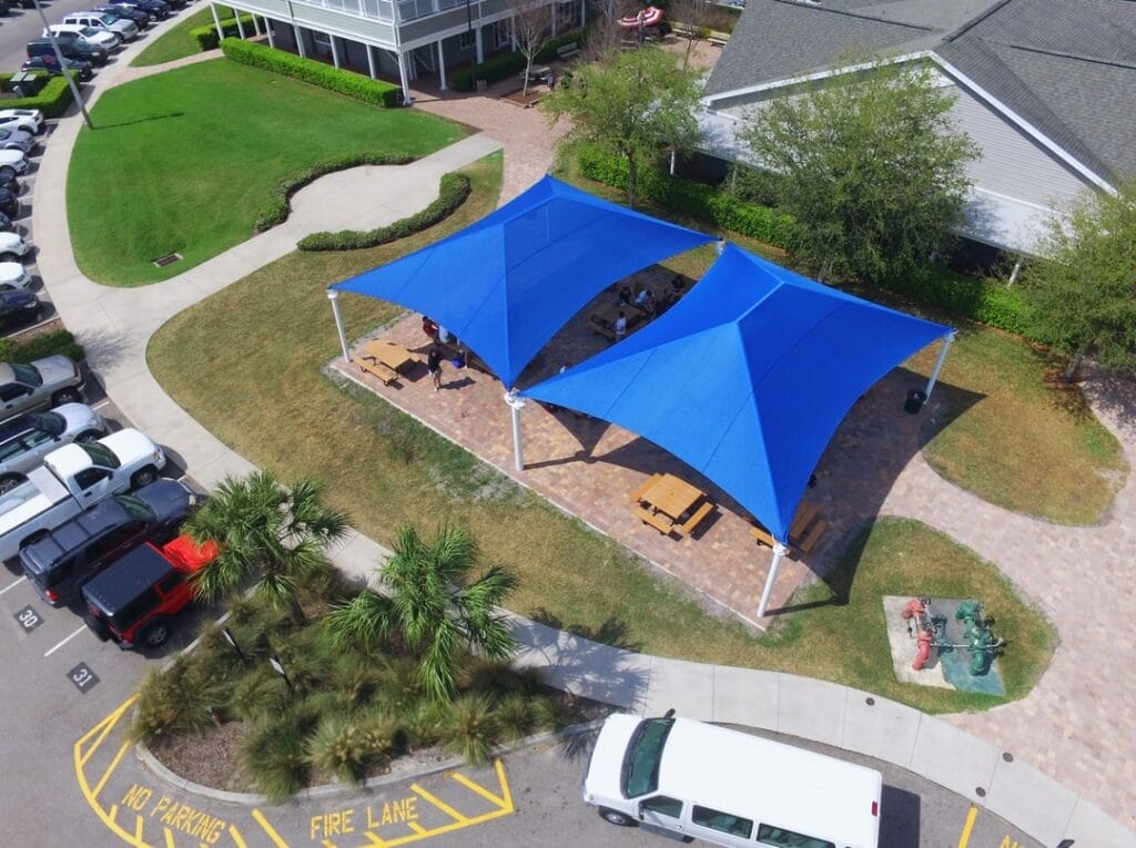 aerial image of shade structures erected over open area with picnic table seating