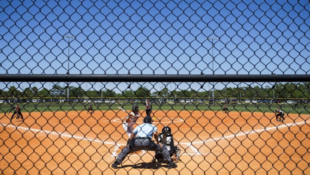image of softball players on the field, at home plate