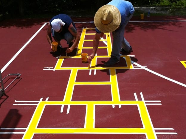 image of two workers resurfacing the basketball court