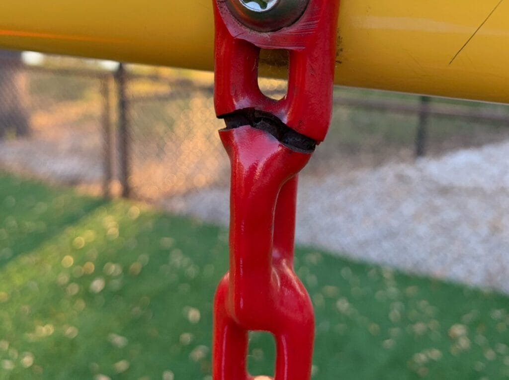 closeup of red, broken chain on playground equipment